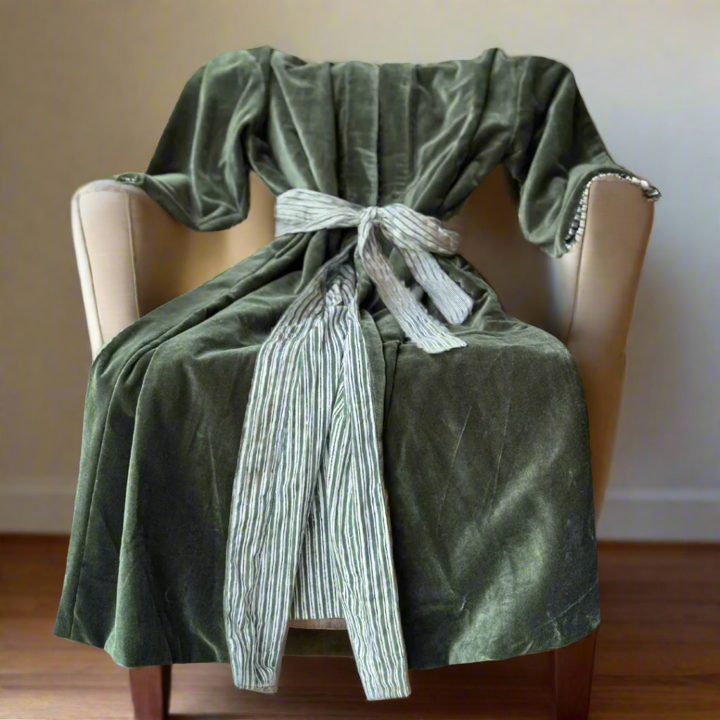 Green blanket draped over a chair with a striped tie, on a neutral background